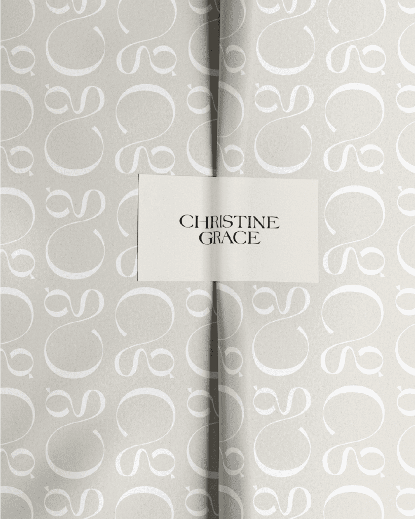 Softly patterned paper wrap with a centered label displaying the Christine Grace logo in sleek black lettering.