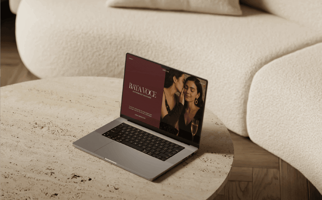 Laptop screen featuring the Baya Voce homepage with luxury branding visuals and elegant typography, placed on a textured travertine table.
