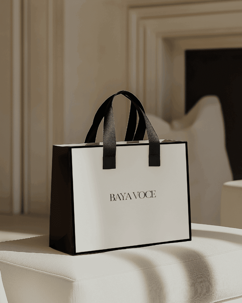 Luxury black-and-white branded shopping bag with Baya Voce logo, symbolizing the tactile, high-end feel of her immersive brand experience.