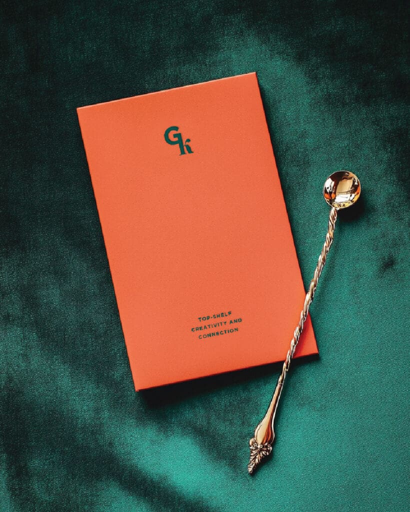 Branded stationery featuring Gk monogram and luxe styling with cocktail accessories, reinforcing the elevated, editorial brand tone.